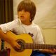 Child playing guitar and singing.