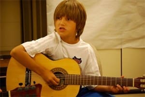 Child playing guitar and singing.