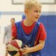 Boy holding a basketball. He has a huge smile and a glint in his eye.