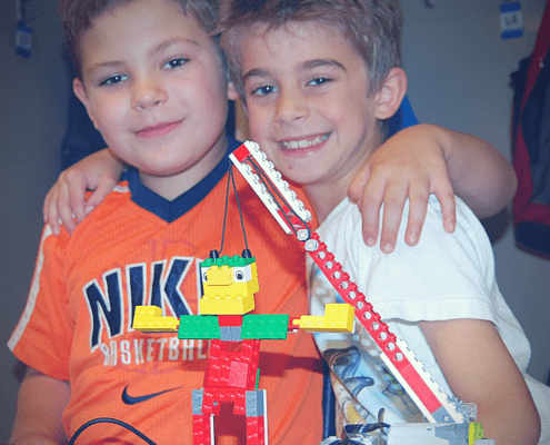 Two buddies get ready to test their waking giant LEGO project.