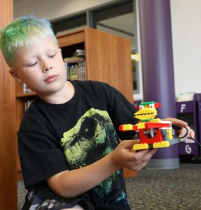 A boy with dyed green hair shows off his Monkey Robot.
