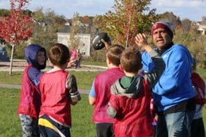 A YEL football coach directs his team.