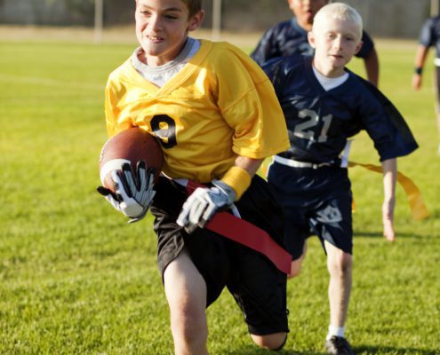 A young flag football player goes for the touchdown.