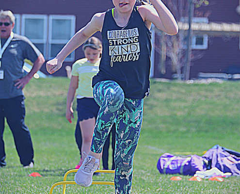 Track and Field classes. Female student going over the hurdles.
