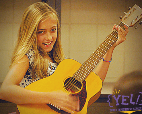 Girl smiling while playing guitar