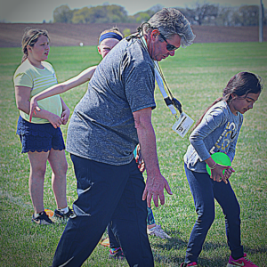 Dynamic coach showing a student how to throw the discus.