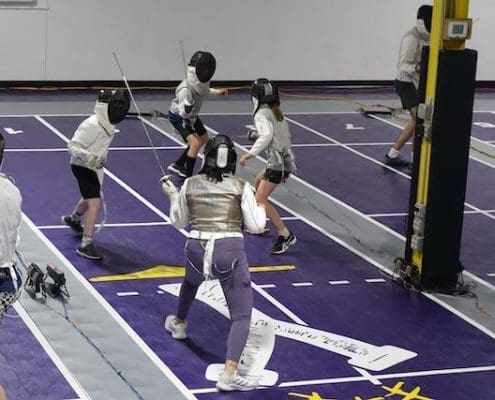 Fencing club with fencers fencing.