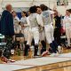 2023 Team State Champions, {YEL!} SE MN Fencing Team. All the teammates are huddled and cheering.