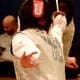 Closeup of a fencer's back delivering an excellent touch against an opponent.