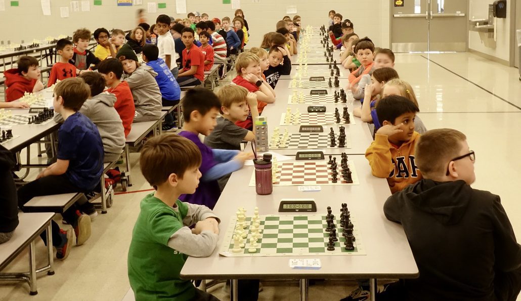 Chess players lined up in long rows of chess boards as they prepare to start their tournament chess games. Chess Club.