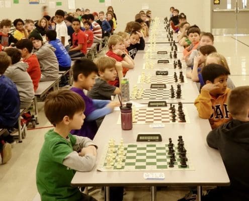 Chess players lined up in long rows of chess boards as they prepare to start their tournament chess games. Chess Club.