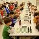 Chess players lined up in long rows of chess boards as they prepare to start their tournament chess games. Chess Club.